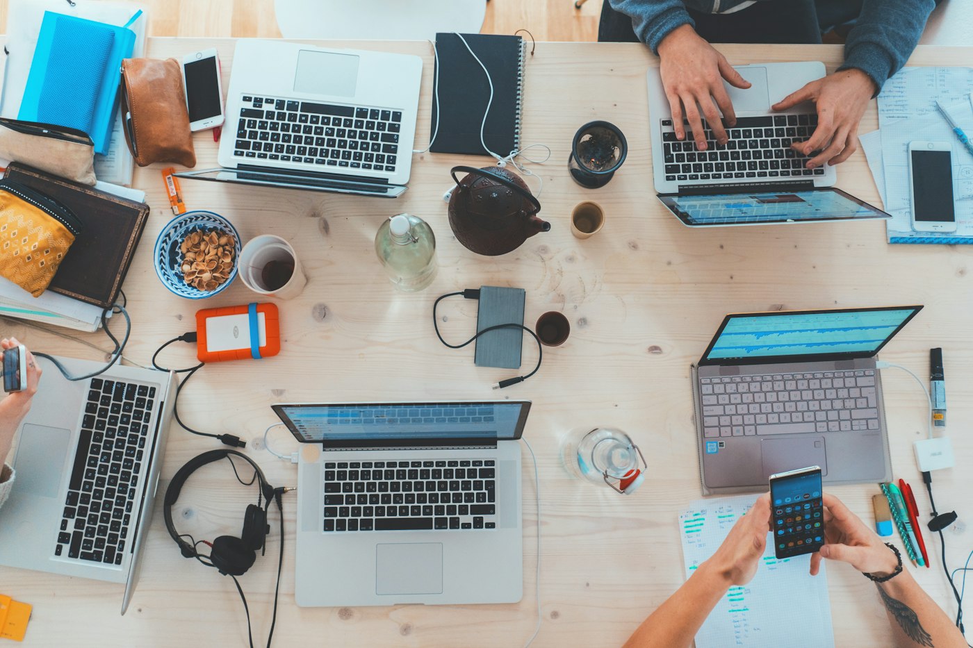 Gemeinsames Arbeiten an einem Tisch mit Laptops und Unterlagen, von oben gesehen.